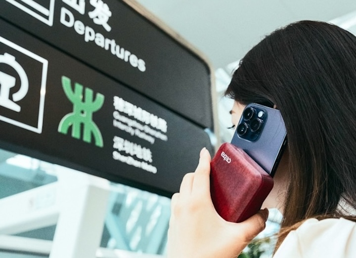 Frau telefoniert mit Powerbank und Smartphone am Flughafen